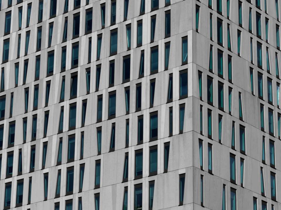 Fachada de concreto claro con una retícula de ventanas de vidrio