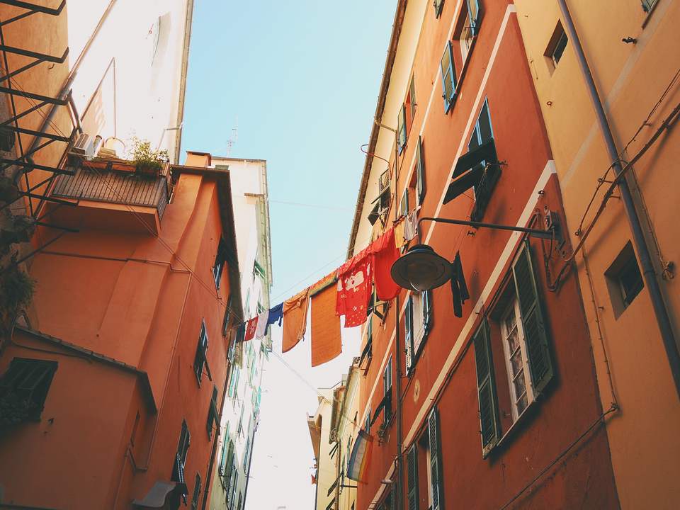 Callejón estrecho entre edificios color terracota, con ropa tendida y una lámpara